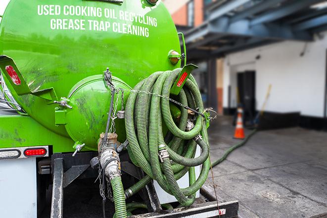 a grease trap being pumped by a sanitation technician in Dorchester, MA